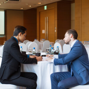 Two serious adult business men sitting at table, working with documents and discussing issue in conference room